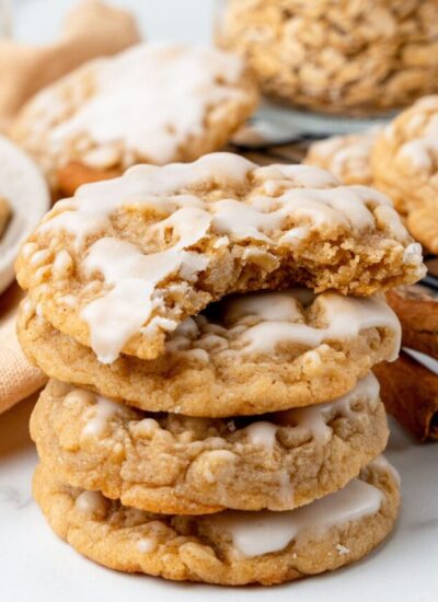 a stack of four iced oatmeal cookies. the top one has a bite taken out.