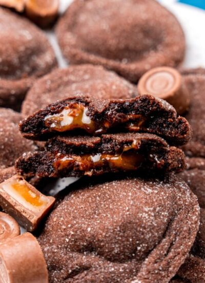 Rolo stuffed cookies. One has been browken in half to show the gooey caramel inside.