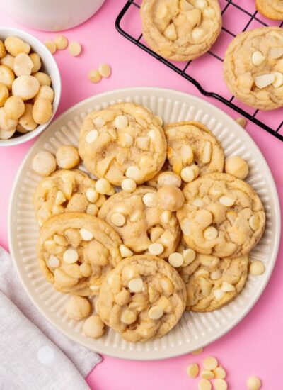 A plate of white chocolate chip macadamia nut cookies on a pink table.