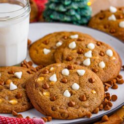 a plate of gingerbread cookies with two types of chocolate chips on a table decorated for the holidays.