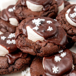 a platter of chocolate hot cocoa cookies topped with marshmallows and chocolate frosting.