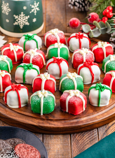Christmas Present Oreo Truffles shown on a wooden tray, with a mug in the background