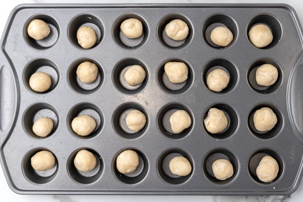 balls of dough added to a wilton mini muffin pan