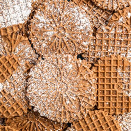 Overhead shot of chocolate pizzelle cookies sprinkled with powdered sugar