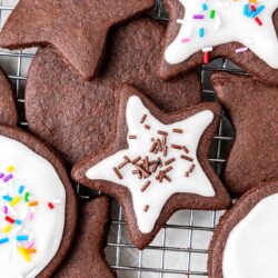 Overhead shot of chocolate sugar cookies on a wire rack, decorated with icing and sprinkles.