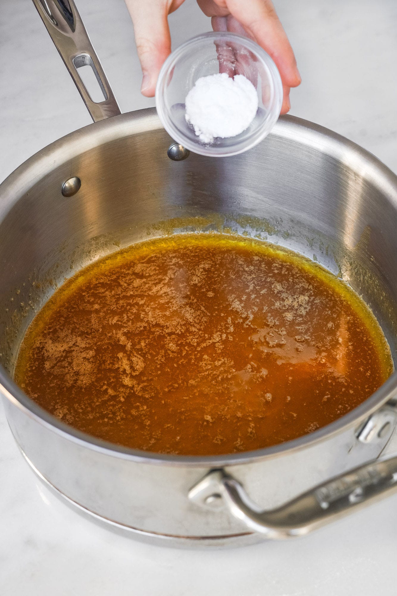 adding baking soda to caramel in a metal saucepan for anzac biscuits.