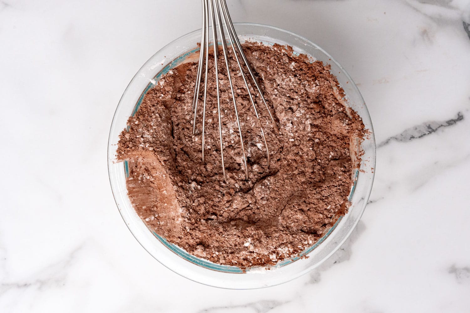 a glass bowl of flour and cocoa powder, stirred with a whisk