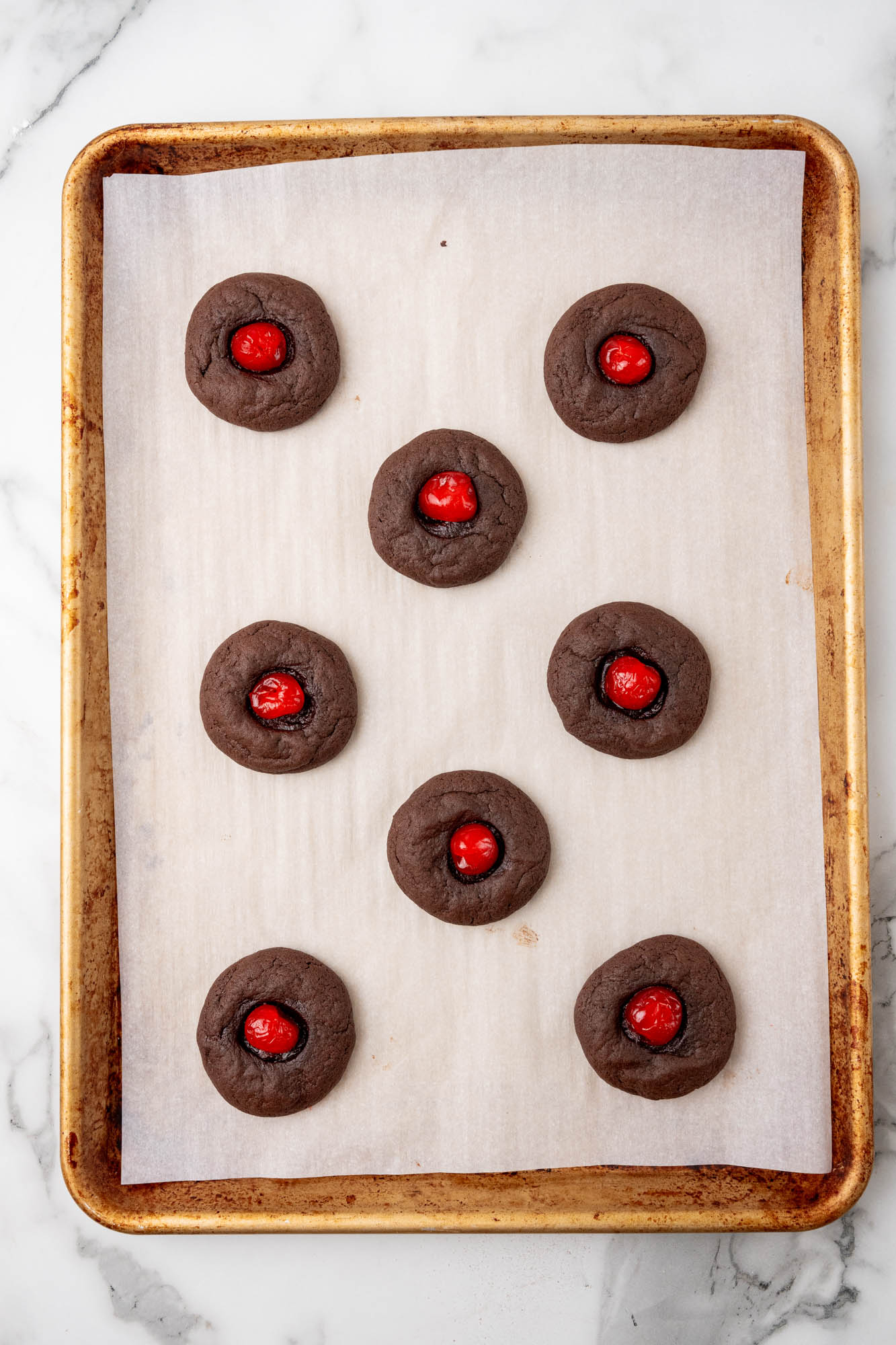 baked chocolate cookies with cherries in the center. top down view.