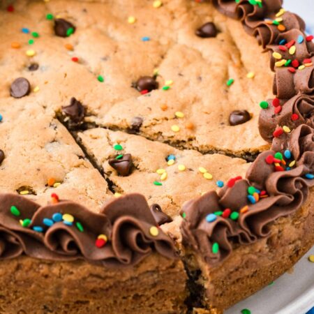 a chocolate chip cookie cake with one wedge cut and slightly removed.