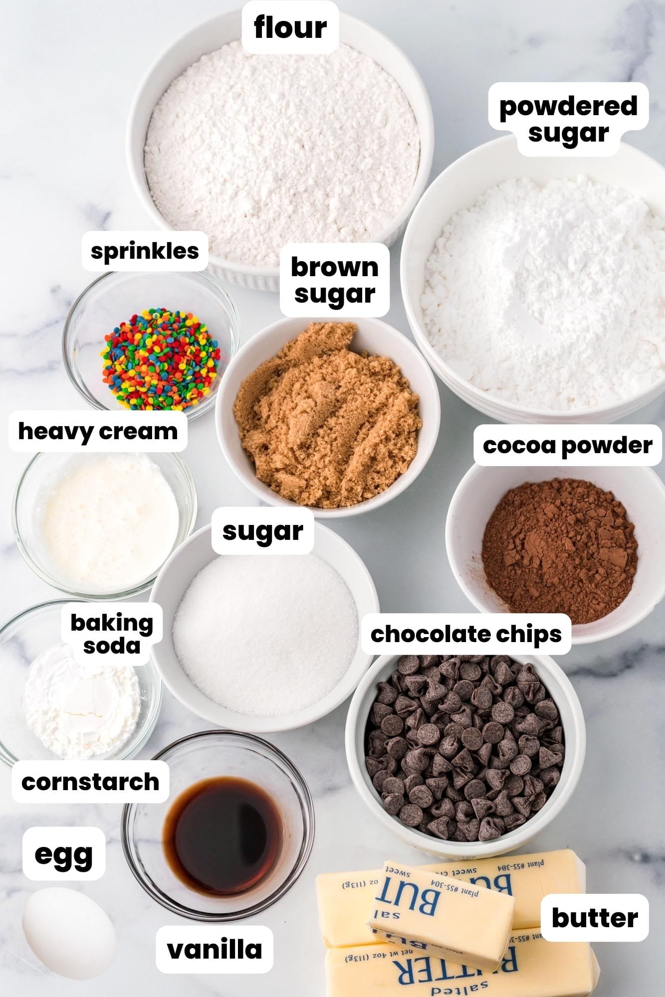 several bowls of baking ingredients arranged on a marble countertop.
