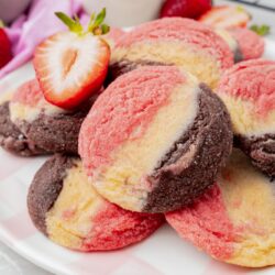 closeup of a plate of neapolitan cookies, garnished with half of a fresh strawberry.