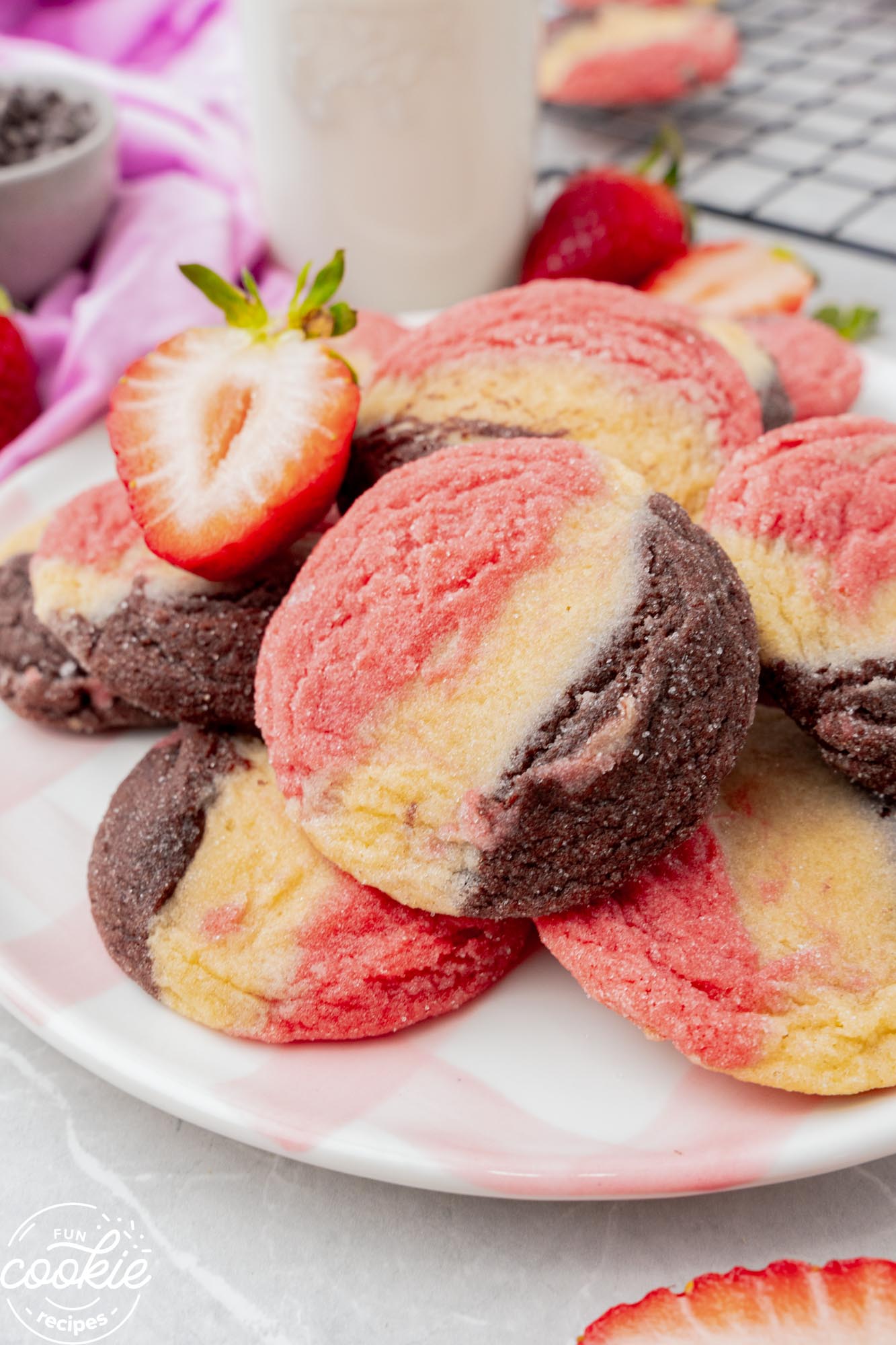 closeup of a plate of neapolitan cookies, garnished with half of a fresh strawberry.