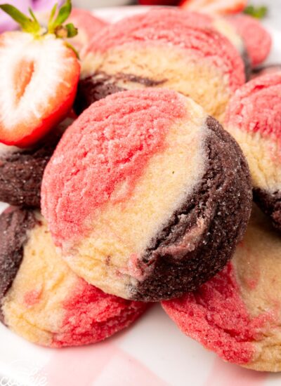 a pile of round cookies with stripes of pink, white, and brown dough.