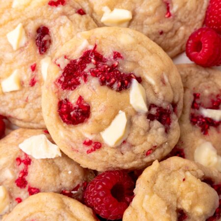 closeup image of cookies with large chunks of white chocolate and fresh raspberries baked in.