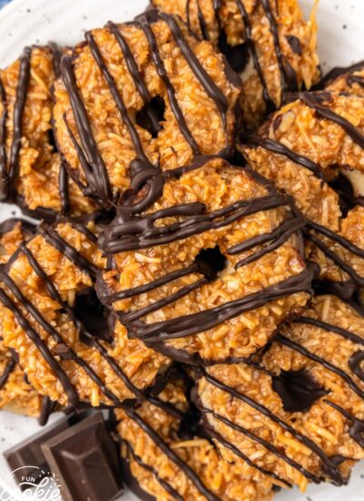 round samoa cookies topped with caramel and coconut and drizzled with dark chocolate, on a plate, viewed from overhead