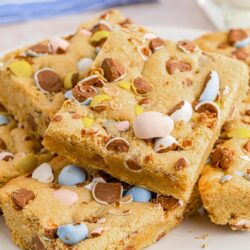Stacked squares of mini egg cookie bars on a white plate