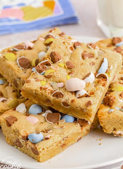 Stacked squares of mini egg cookie bars on a white plate