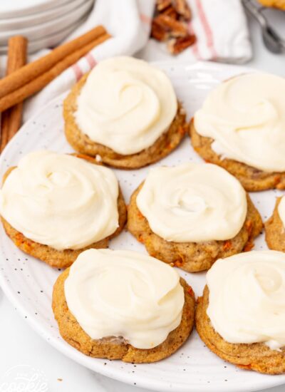 a white plate holding carrot cake cookies with cream cheese frosting.
