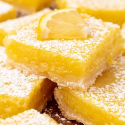 cut lemon squares on a wooden surface, dusted with powdered sugar.