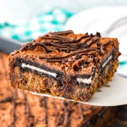 a spatula holding up one square of Oreo Brookie to show the layers of cookie, brownie, and oreos.