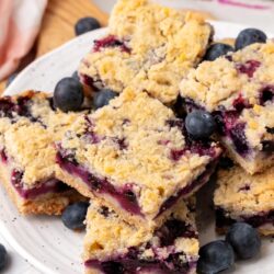 a plate filled with blueberry cookie bars and fresh blueberries.