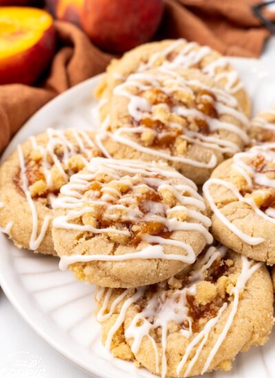 a plate holding cookies filled with peach cobbler, drizzled in icing.