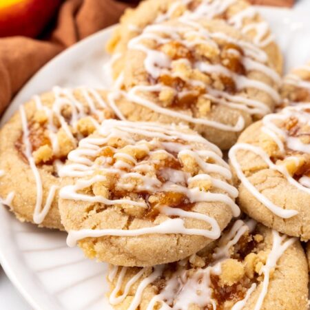 a plate holding cookies filled with peach cobbler, drizzled in icing.
