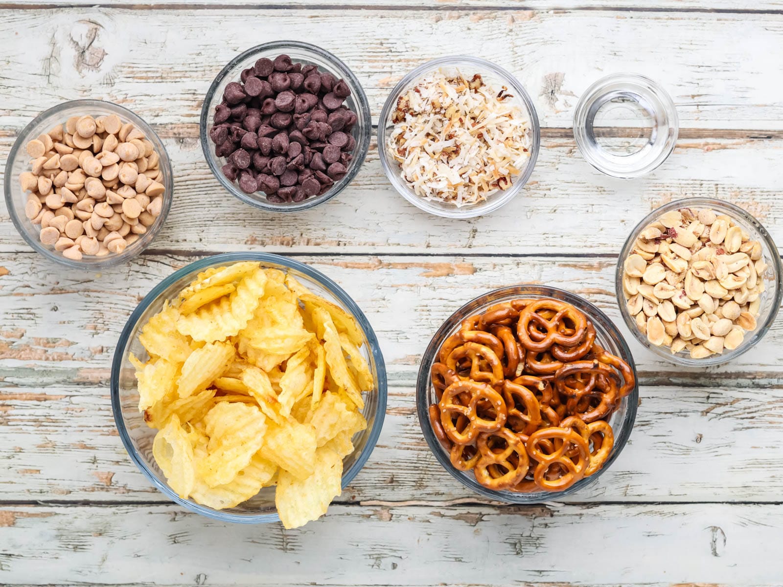 Crunchy ingredients for chocolate potato chip clusters combined in a glass mixing bowl.